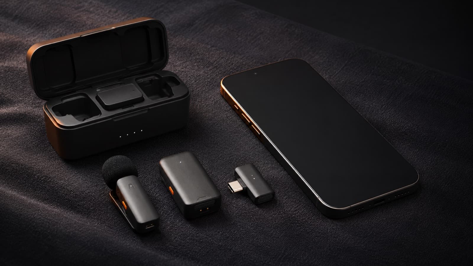 Un micrófono de solapa inalámbrico (estuche, transmisor y receptor USB-C) junto a un celular
