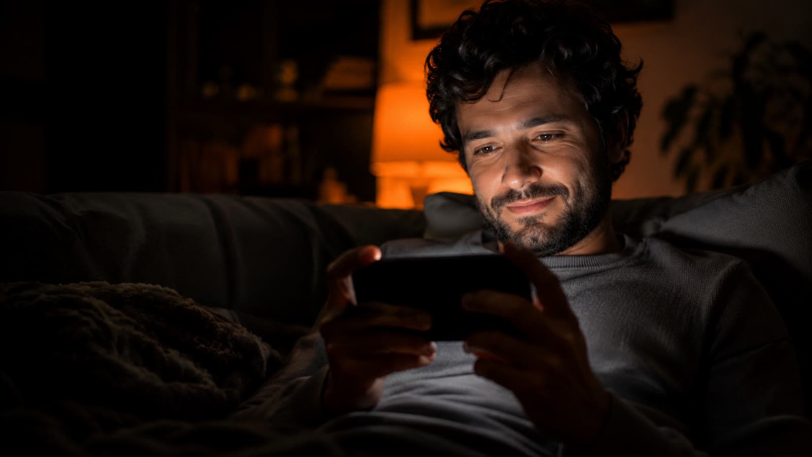 Un alumno mirando una clase en el celular, de noche