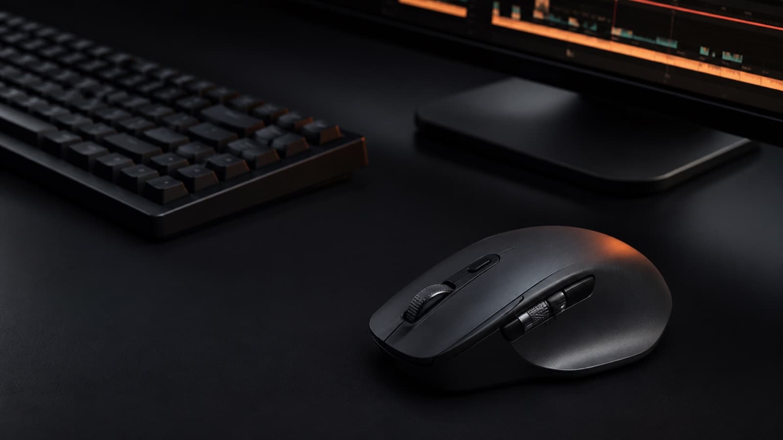A dark editing desk with a mechanical keyboard, a monitor showing a timeline, and a productivity mouse with side controls in focus