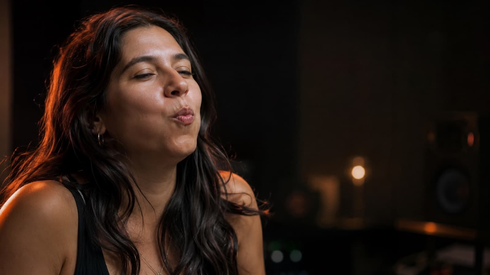 Persona haciendo vibración de labios (“brrr”) de calentamiento vocal en un rincón de grabación