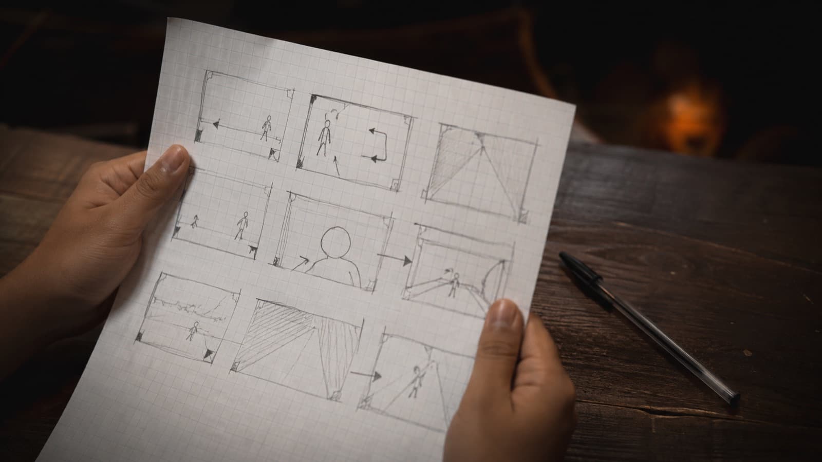 Hands holding a hand-drawn storyboard with stick figures, boxes and arrows