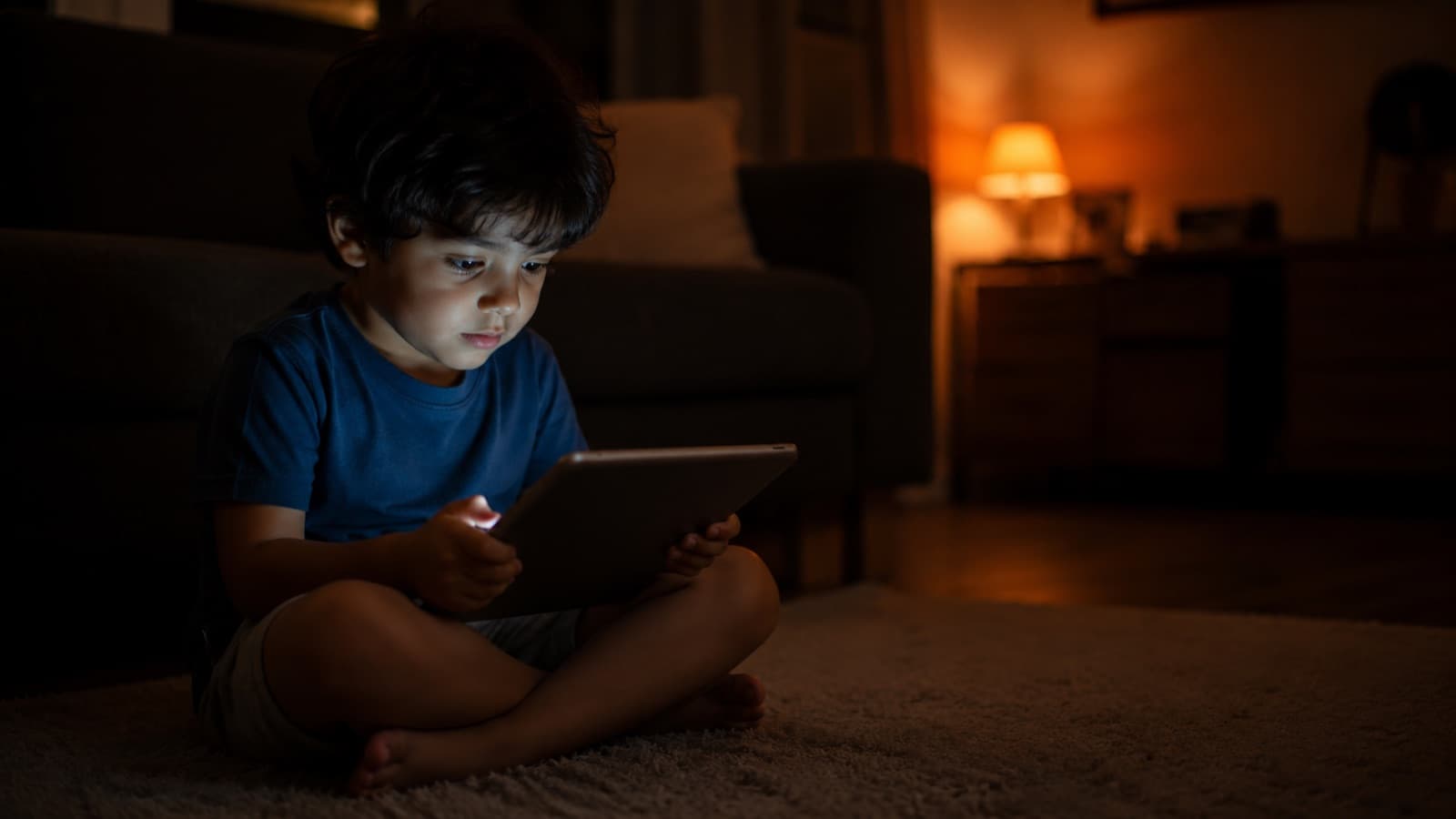 A child watching a video on a tablet, face lit by the screen